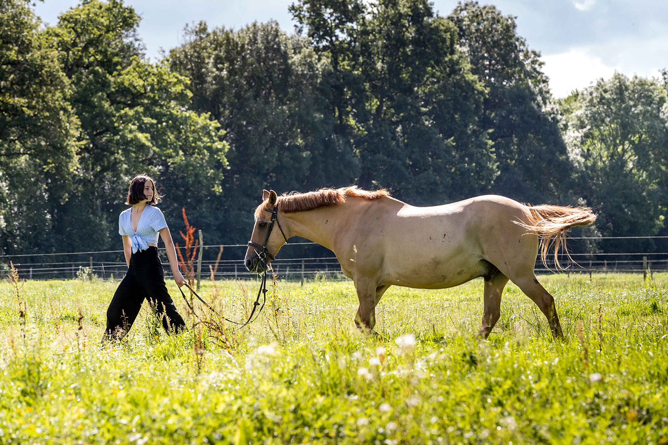 Photo d'une jeune fille tenant son cheval en extérieur